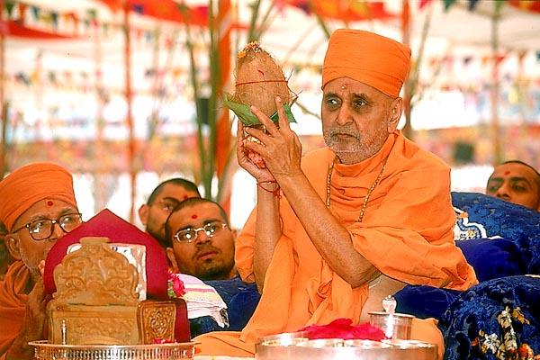 Swamishri holds the auspicious pot and shrifal during the rituals