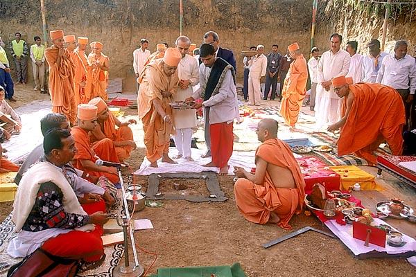 Swamishri sprinkles water, kumkum, etc as part of the shilanyas rituals