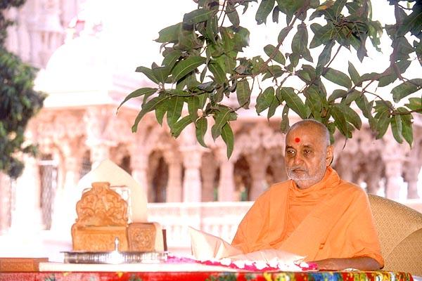 Swamishri performs his morning puja with the Shri Swaminarayan Mandir, Sankari in the backdrop