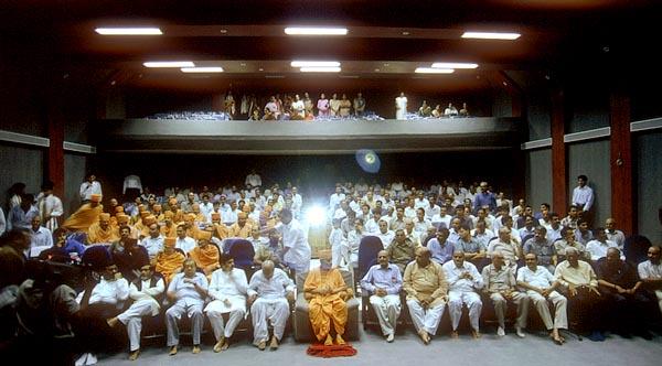 Swamishri and guests view a visual presentation in the Institute's auditorium