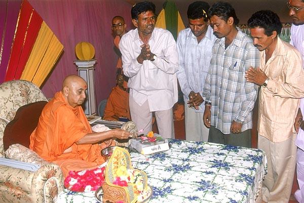 Swamishri sanctifies the bricks with rice grains, flowers, gulal and holy water for the school in Paandri village
