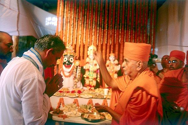 Swamishri blesses Shri Divyasinghdev and devotees by showering rice grains