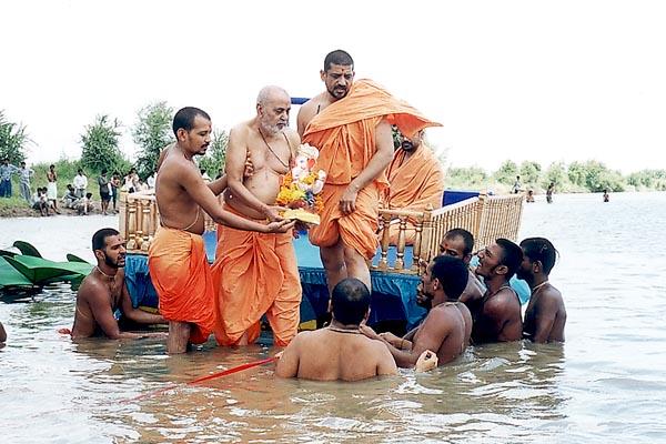Swamishri enters the river and prepares to take a holy dip