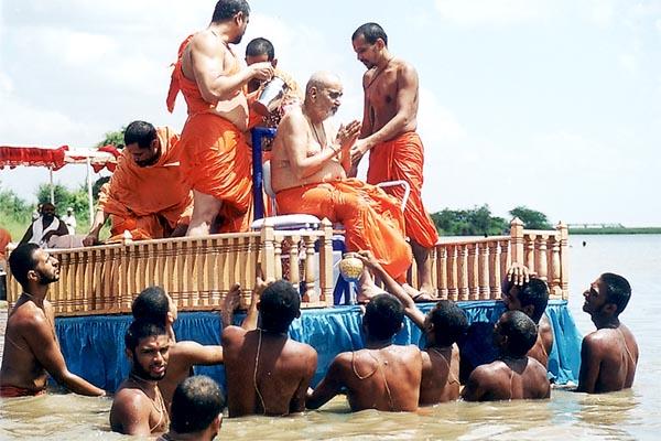 Swamishri bathes with fresh water after emerging from his holy dip