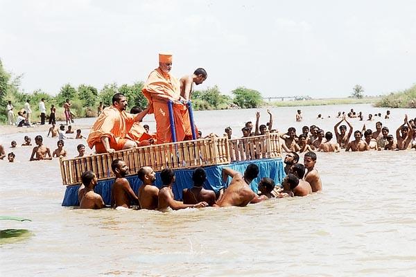Sadhus pull Swamishri's decorated raft back to river bank