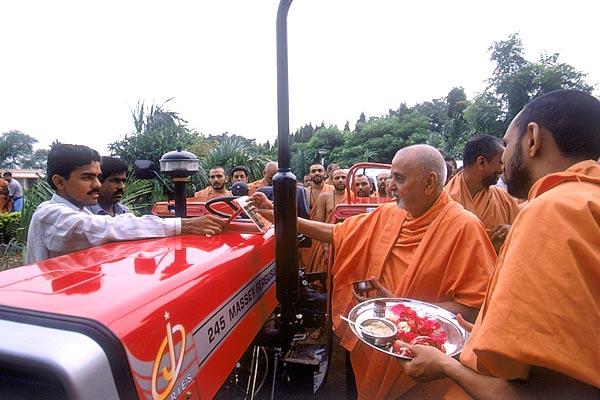 Swamishri sanctifies several tractors for the earthquake rehabilitation project in Kutch 	