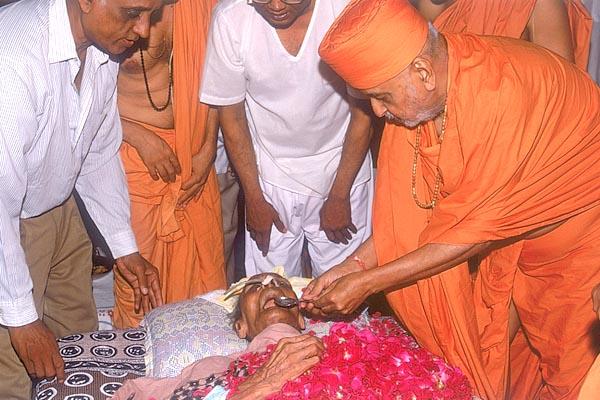 Swamishri places a teaspoonful of holy water in Prabhudasbhai's mouth 