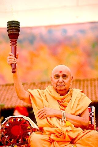 Swamishri holding aloft a torch carried by a team of 31 youths who pilgrimaged on foot from Amdavad to Sarangpur (156 Kms)