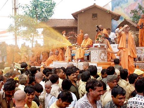 In a joyous mood, Swamishri profusely showers the holy water on the devotees and sadhus. About 43,000 devotees had assembled for the Fuldol festival