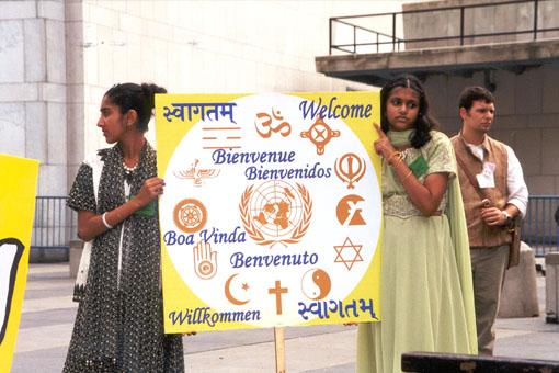BAPS volunteers with a multi-language banner of Welcome for the international delegates
