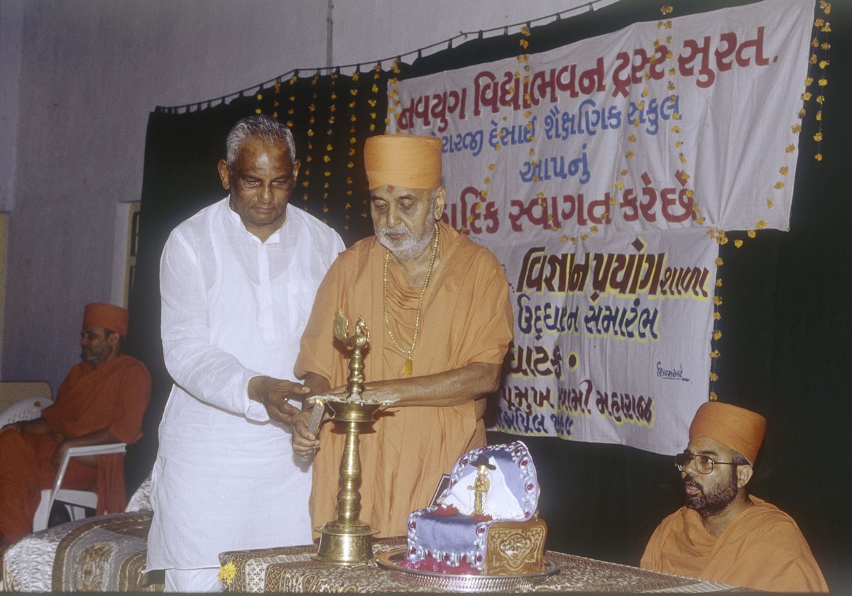 Swamishri and a dignitary light the inaugural lamp for the new Vigyan Prayog Shala in the Navyug Vidyabhavan Trust, Surat