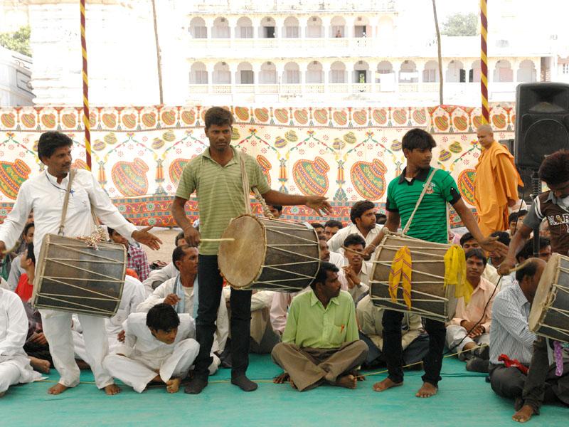 Tribal devotees play drums before Swamishri