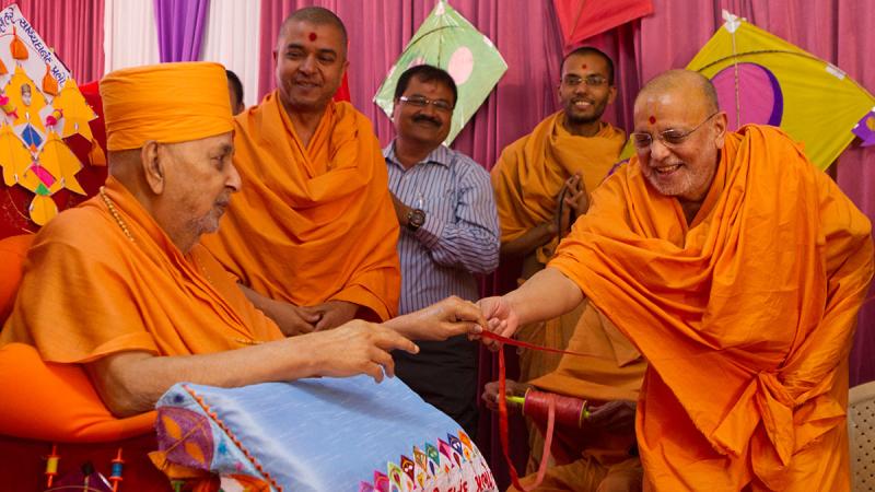  Pujya Ishwarcharan Swami gives the string of a kite in Swamishri's hands