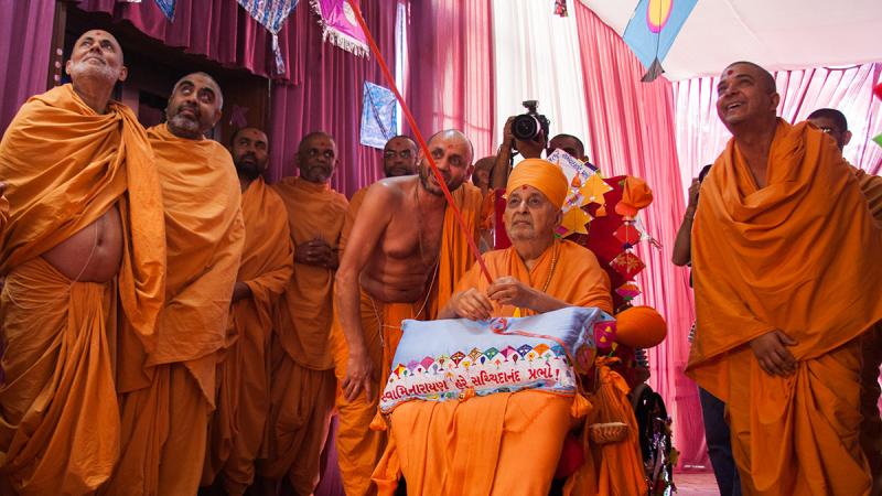 Swamishri holds the string of a kite in his hands