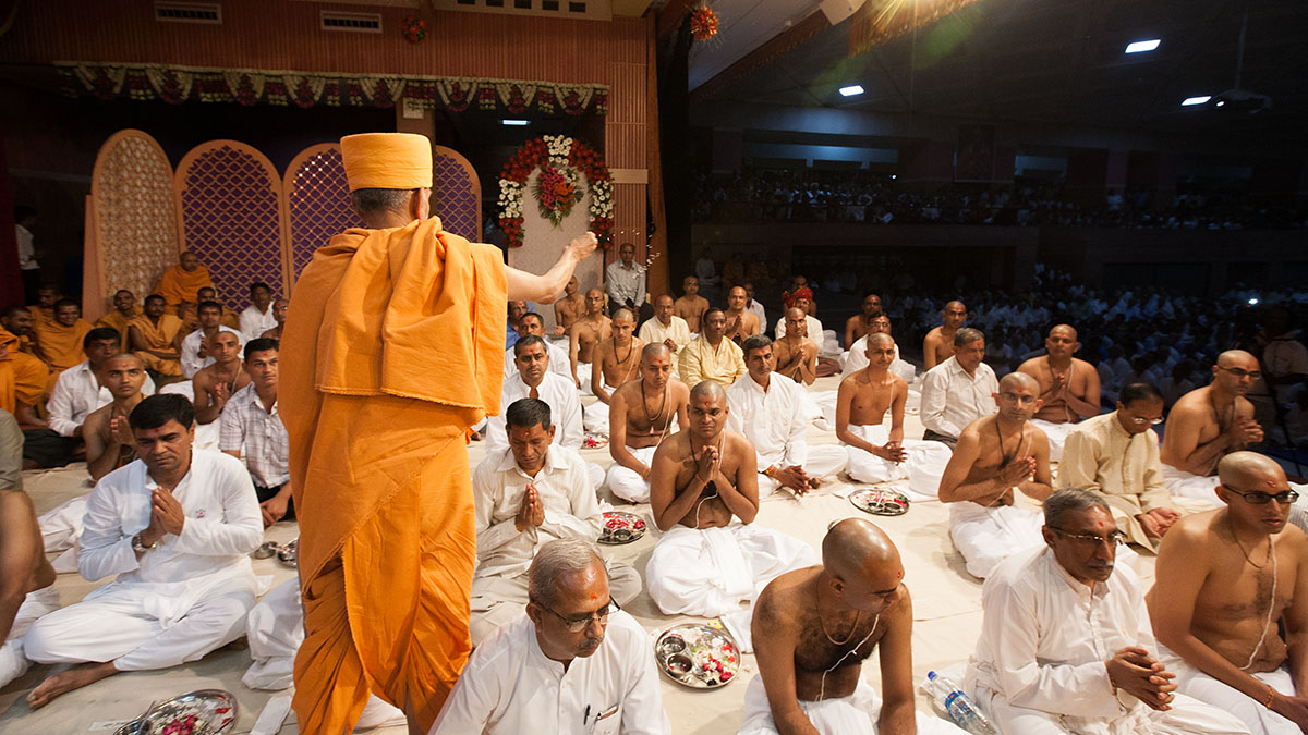 Pujya Mahant Swami blesses sadhaks and their fathers by showering rice grains