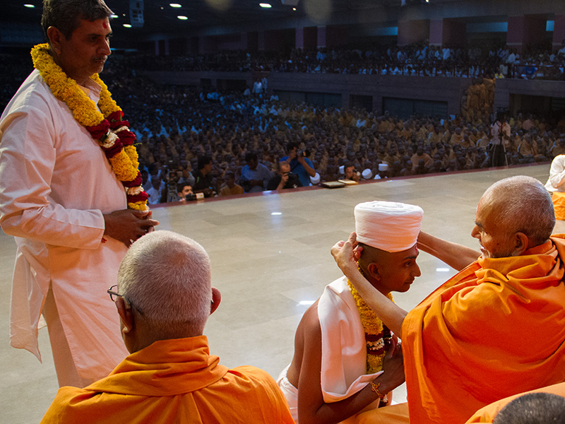 Pujya Mahant Swami puts on the 'paag' for a newly initiated parshad