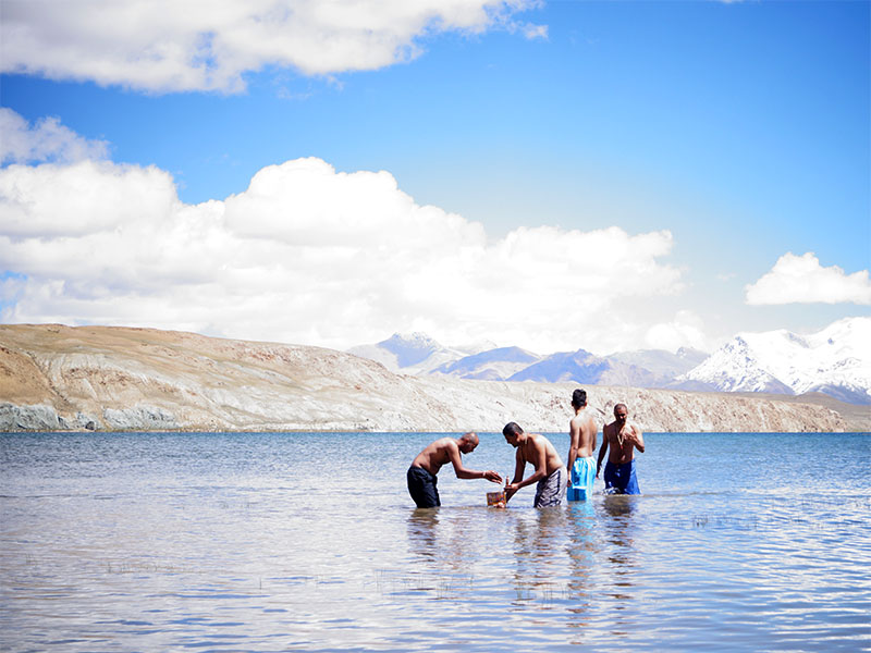 Youths bathe the murti of Nilkanth Varni in the freezing waters of Manasarovar lake