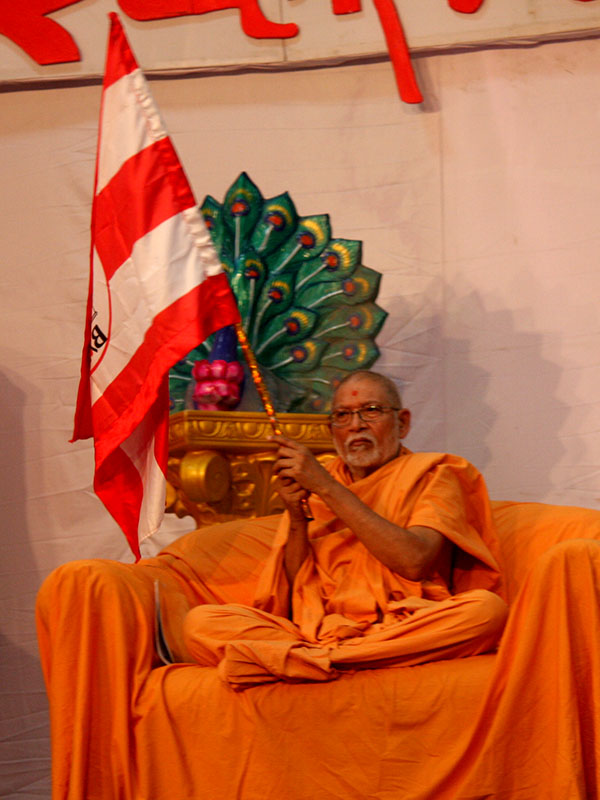 Pujya Bhaktipriya (Kothari) Swami waves the BAPS flag at the Bhavnagar Youth Shibir, Sankari, India