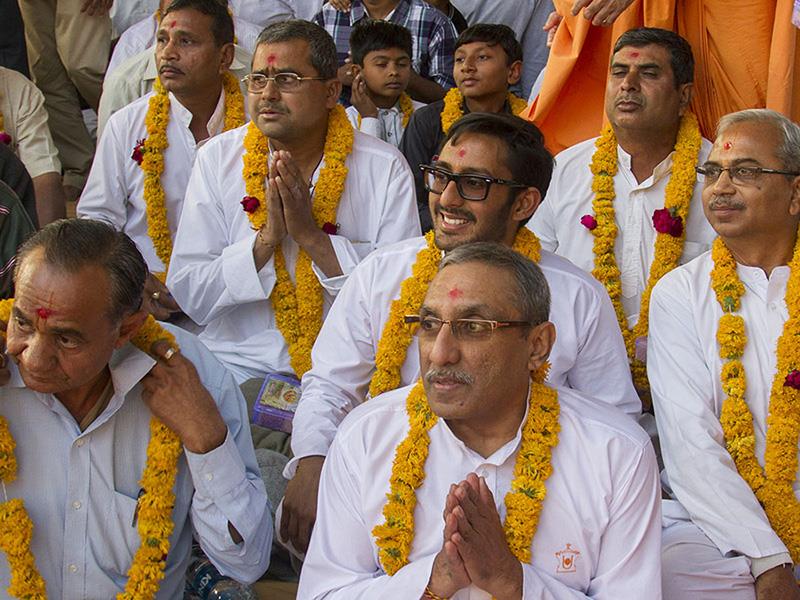 Fathers of the newly initiated sadhus are honored with garlands