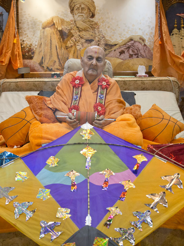Swamishri holds the string of a kite in his hands