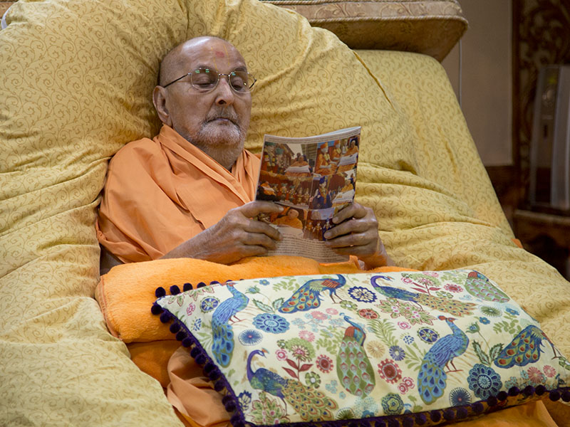 Swamishri reads the latest issue of Swaminarayan Prakash in the evening