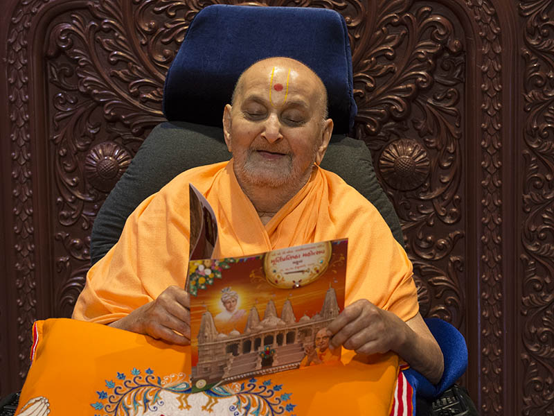 Swamishri reads the invitation card for inauguration of the new shikharbaddh BAPS Shri Swaminarayan Mandir at Mahuva, India - the birthplace of Brahmaswarup Bhagatji Maharaj