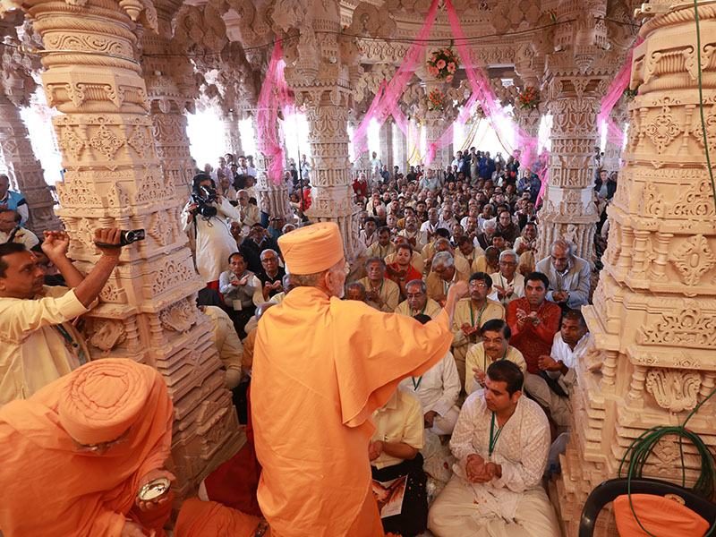 Pujya Mahant Swami blesses devotees by showering rice grains