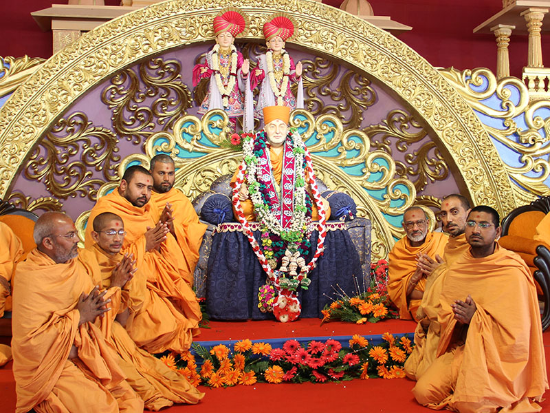 Sadhu honor Swamishri's murti with a garland