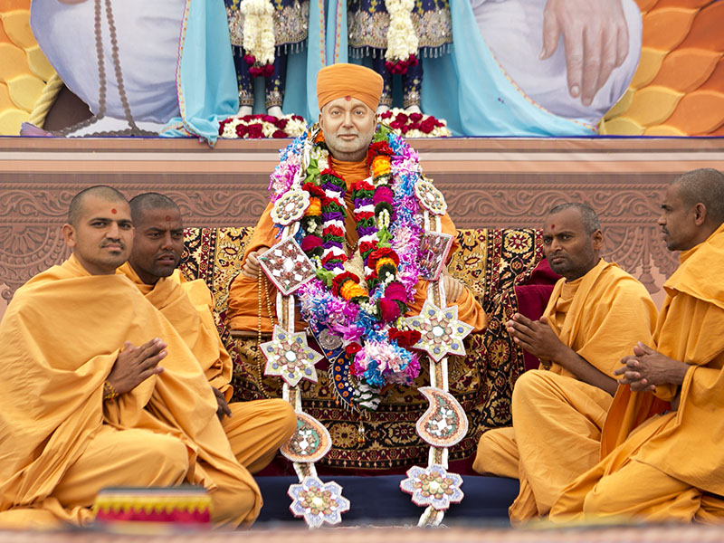 Sadhus serving at Mahuva Mandir honor Swamishri's murti with a garland
