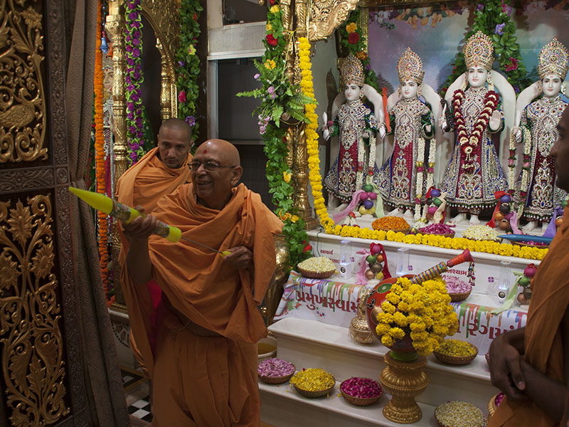 Pujya Tyagvallabh Swami and senior sadhus spray sanctified colored water and flowers on sadhus