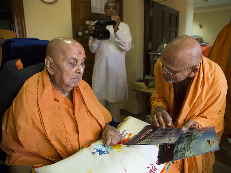 Swamishri sanctifies an invitation card for Robbinsville Mandir Mahotsav