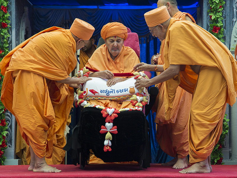Pujya Kothari Swami and Pujya Tyagvallabh Swami honor Swamishri with a garland