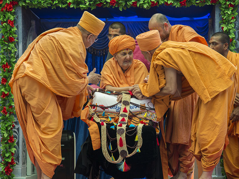 Pujya Ishwarcharan Swami and Pujya Viveksagar Swami honor Swamishri with a garland