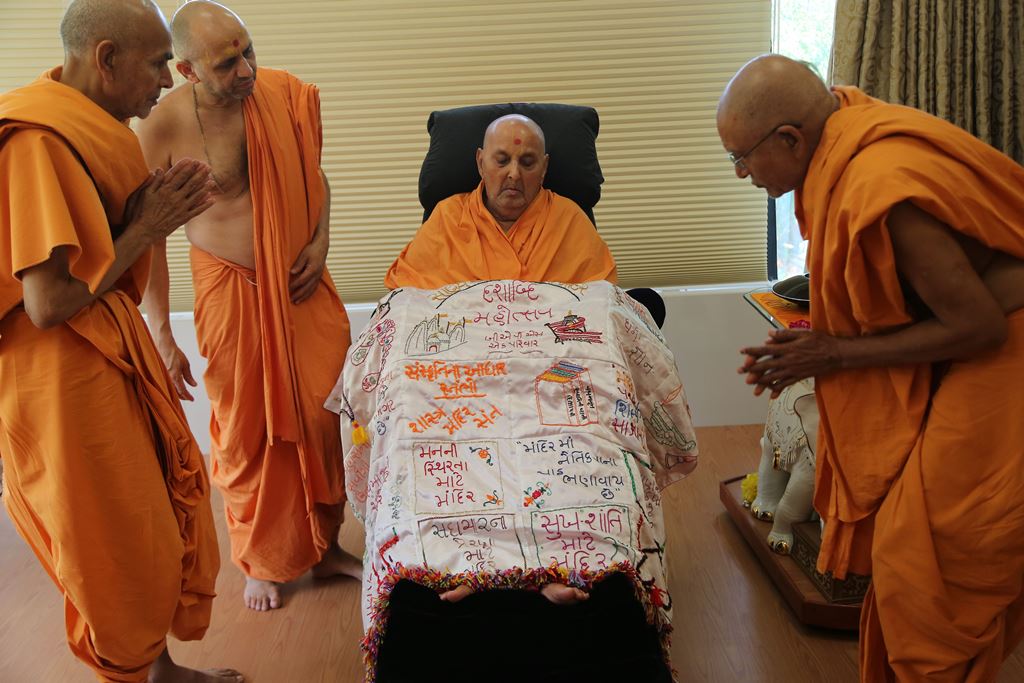 Senior sadhus honour Swamishri in Sarangpur with a special shawl commemorating the Mandir’s 10th anniversary