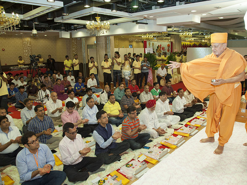 Pujya Ishwarcharan Swami blesses devotees by showering rice grains