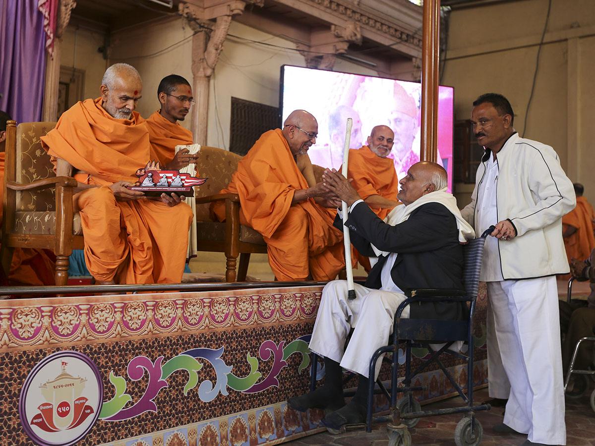 Pujya Keshavjivan Swami (Pujya Mahant Swami) presents mementos to the devotees