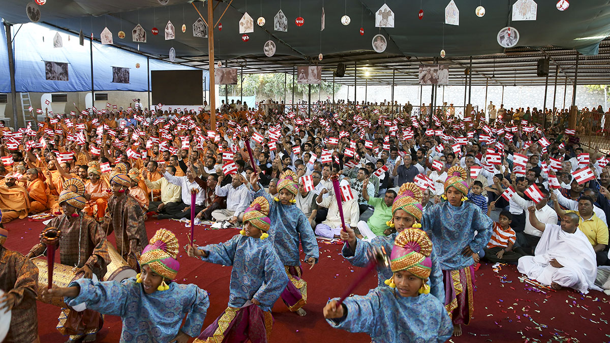 Sadhus and devotees doing darshan of Swamishri while children perform a cultural dance