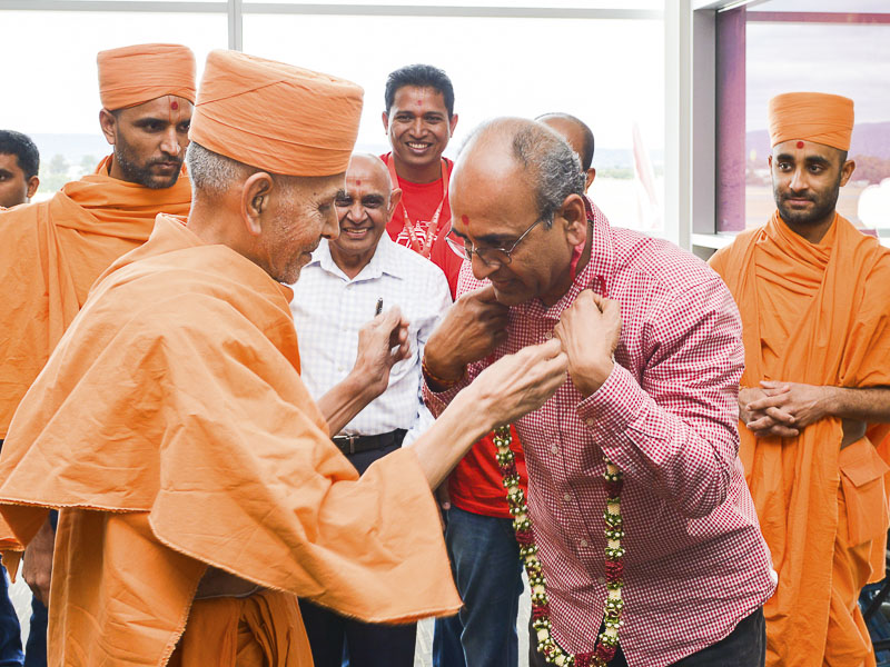 Pujya Mahant Swami welcomed with garlands at airport