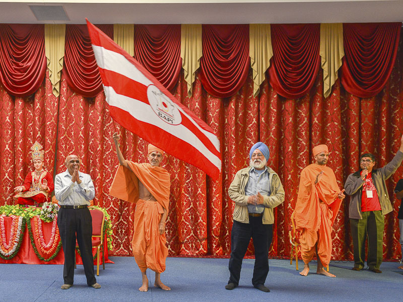 Pujya Mahant Swami waves a BAPS flag at the Swagat Sabha and Bal Din held at BAPS Shri Swaminarayan Mandir, Adelaide