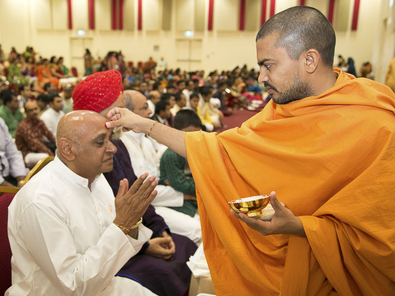 Sadhus apply a chandlo on devotees' foreheads